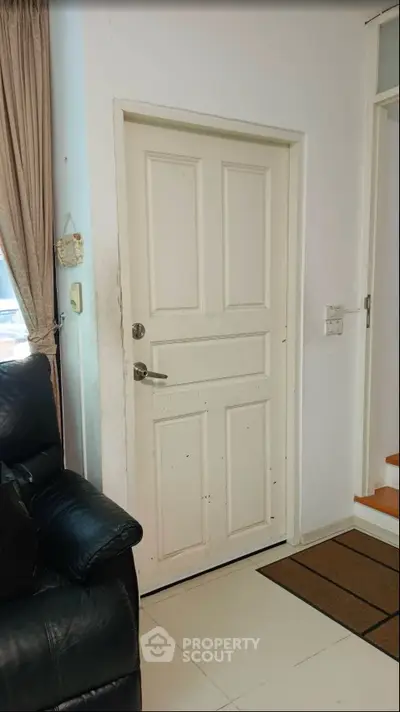 Cozy interior with a white door and leather sofa, perfect for a welcoming home entrance.