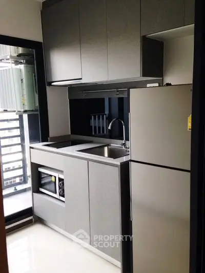 Modern compact kitchen with sleek cabinetry and built-in appliances in urban apartment.