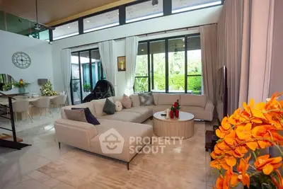 Luxurious living room with modern decor and large windows overlooking lush greenery.