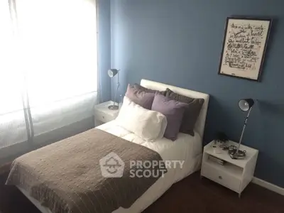 Cozy bedroom with blue walls and stylish decor, featuring a comfortable bed and modern lighting.