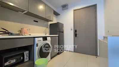 Modern kitchen with sleek appliances and washing machine in compact layout.