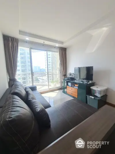 Modern living room with large windows and city view, featuring sleek furniture and natural light.