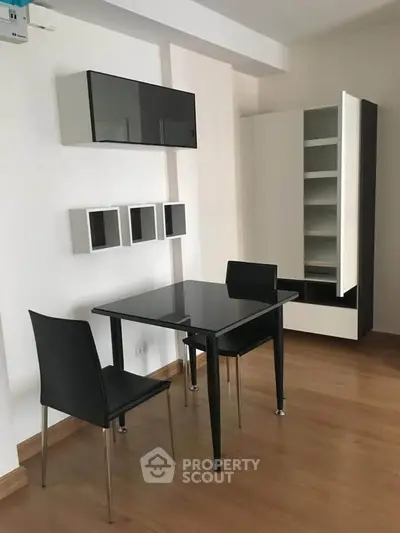 Modern minimalist dining area with sleek black table and chairs, stylish storage solutions.