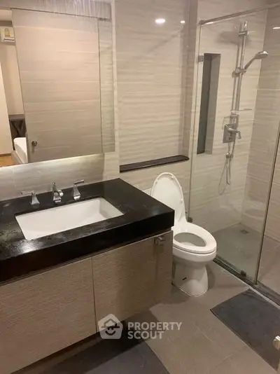 Modern bathroom with sleek fixtures and glass shower enclosure in a contemporary apartment.