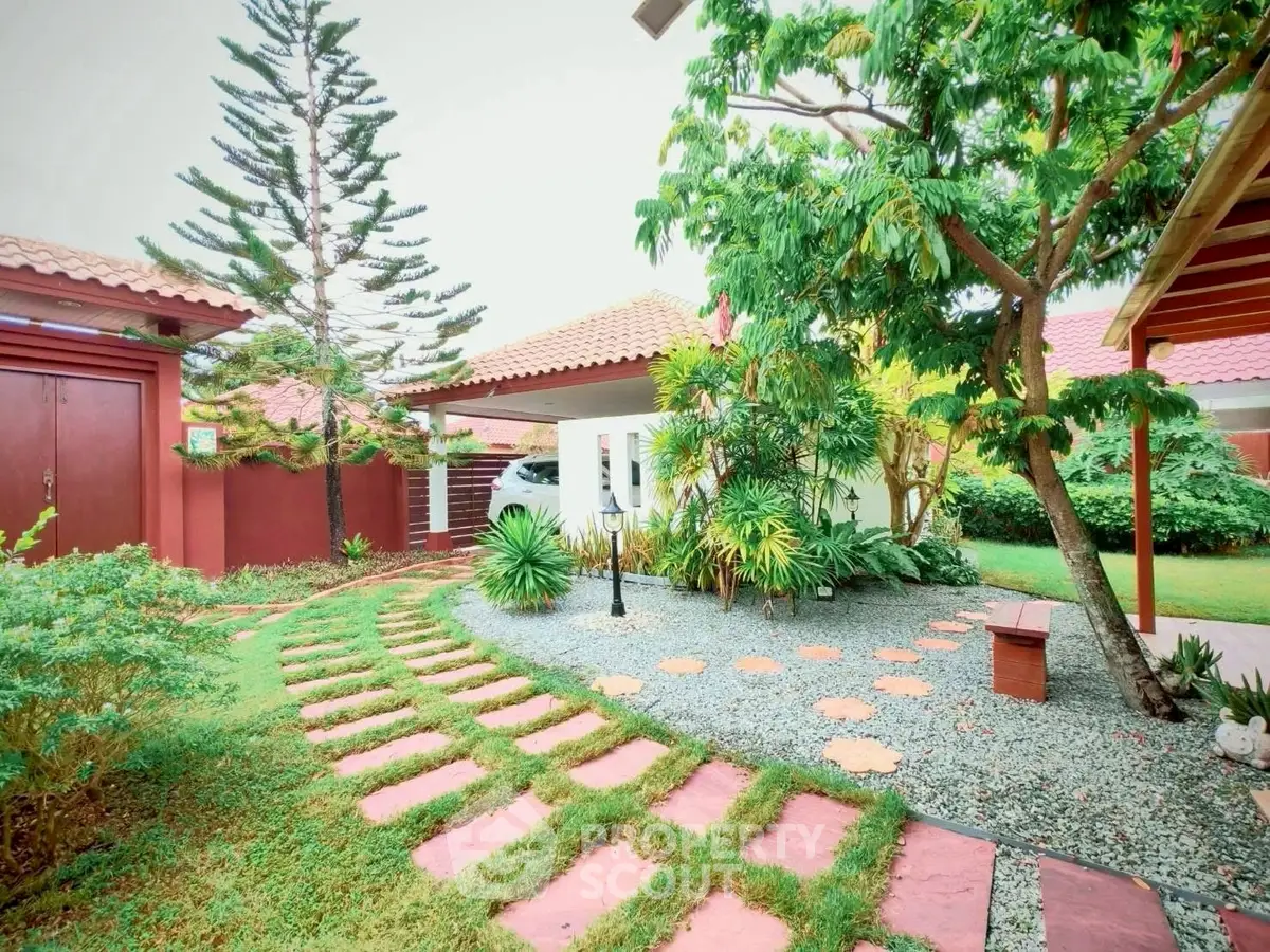 Charming garden with lush greenery and stone pathway in a serene residential setting.