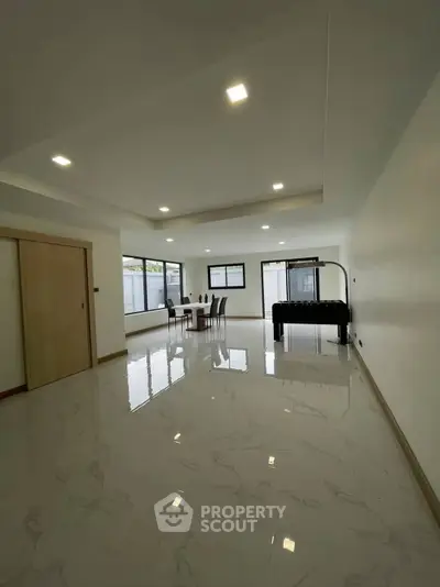 Spacious modern living room with glossy marble floors and large windows for natural light.