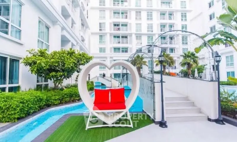 Luxurious apartment complex with unique heart-shaped seating by the poolside.