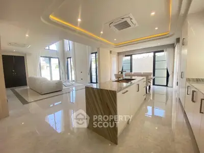 Luxurious open-plan living room with modern kitchen island and high ceilings.