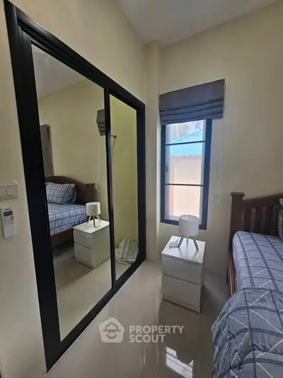 Cozy bedroom with mirrored closet and natural light from window