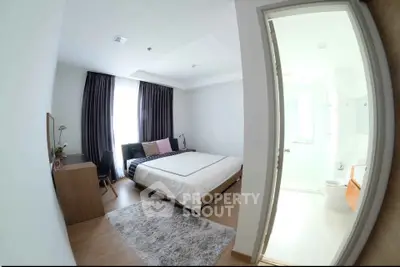Modern bedroom with ensuite bathroom, featuring cozy decor and natural light.