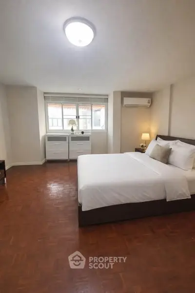 Spacious bedroom with elegant decor and natural light in modern apartment.