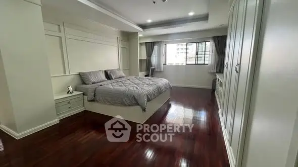 Spacious bedroom with elegant hardwood floors and large window offering natural light.