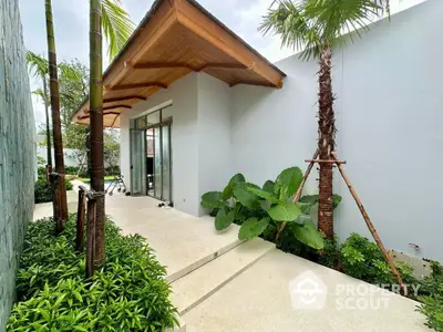 Modern tropical garden entrance with lush greenery and sleek architectural design.