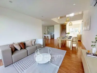 Spacious open-plan living room with modern decor and dining area, featuring natural light and stylish furnishings.