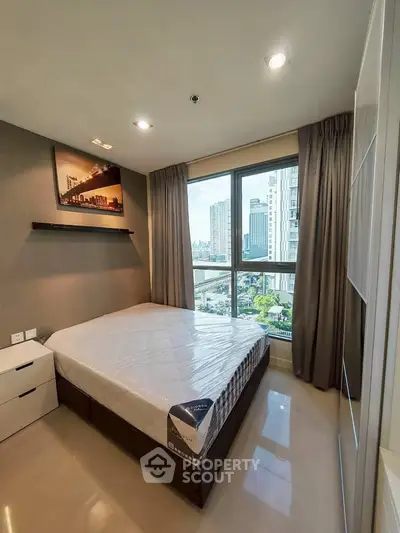 Modern bedroom with city view, featuring large window and stylish decor.