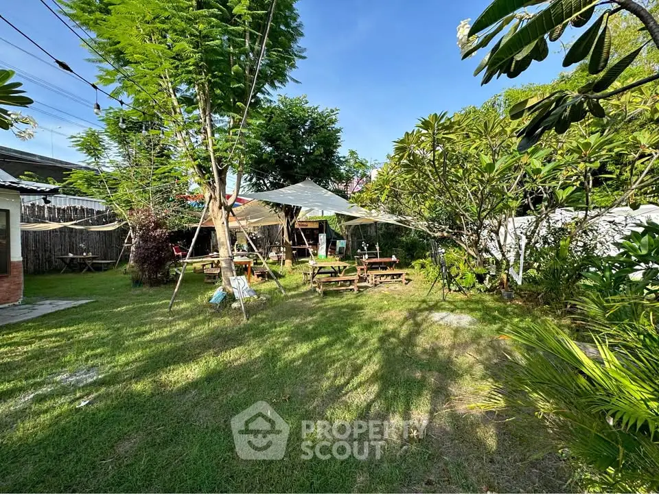 Charming garden area with lush greenery and picnic tables, perfect for outdoor relaxation and gatherings.