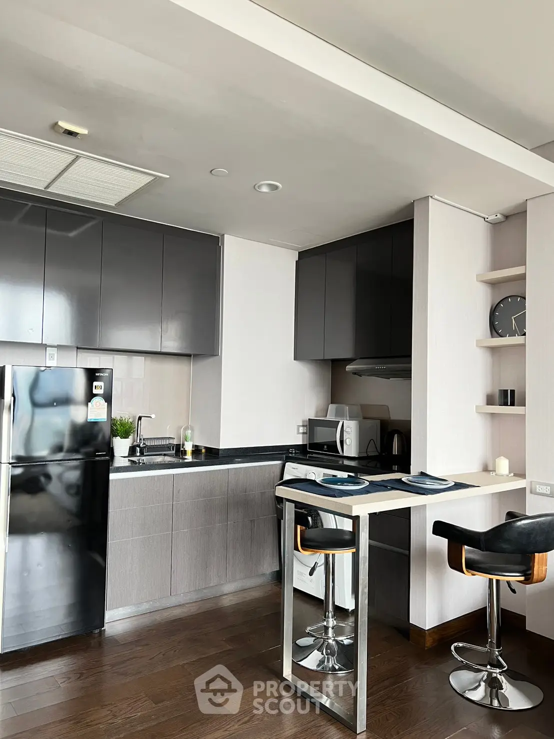 Modern kitchen with sleek cabinetry, breakfast bar, and stainless steel appliances in a stylish apartment.