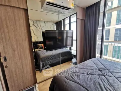 Modern bedroom with mirrored closet and large window view in urban apartment