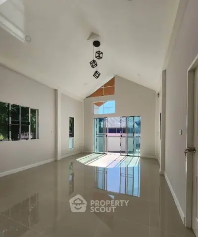 Spacious modern living room with high ceiling and large windows for natural light.