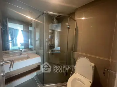 Modern bathroom with glass shower and sleek fixtures in contemporary apartment.
