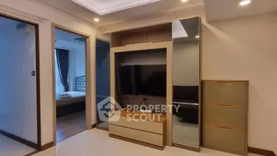 Modern apartment interior with sleek TV unit and mirrored accents, showcasing a cozy bedroom and living area.