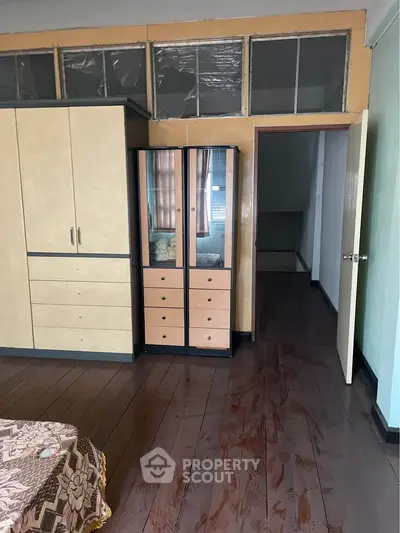 Spacious bedroom with wooden flooring and ample storage in a cozy apartment.