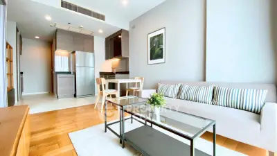Modern living room with open kitchen, stylish furniture, and natural light.