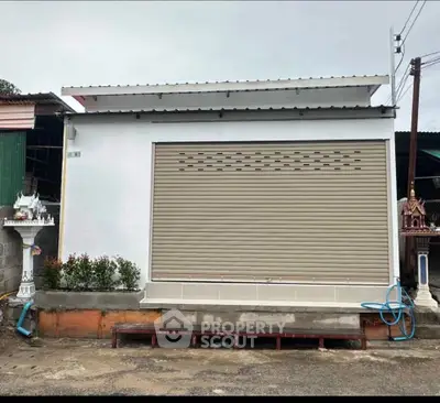 Compact commercial property with secure roller shutter and modern facade.