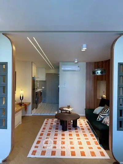 Stylish living room with modern decor and open kitchen layout, featuring cozy seating and contemporary lighting.