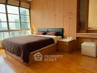 Spacious bedroom with large windows offering city views, featuring wooden flooring and built-in storage.