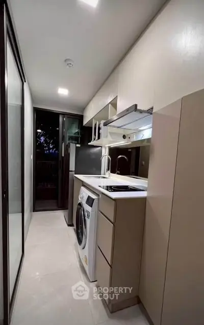 Modern kitchen with sleek appliances and washing machine in compact layout