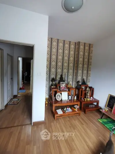 Charming living room with elegant wallpaper and wooden flooring, featuring a decorative display area.