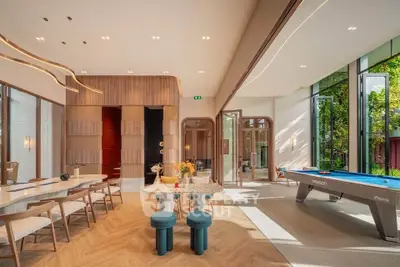 Luxurious modern living room with pool table and elegant dining area, featuring floor-to-ceiling windows and stylish decor.