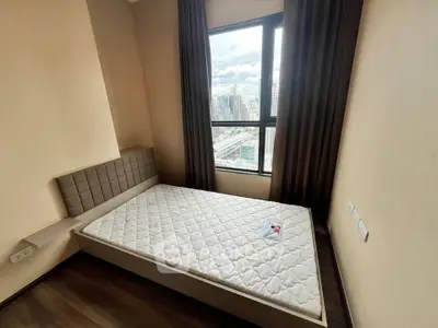 Cozy bedroom with city view, featuring a comfortable bed and large window.