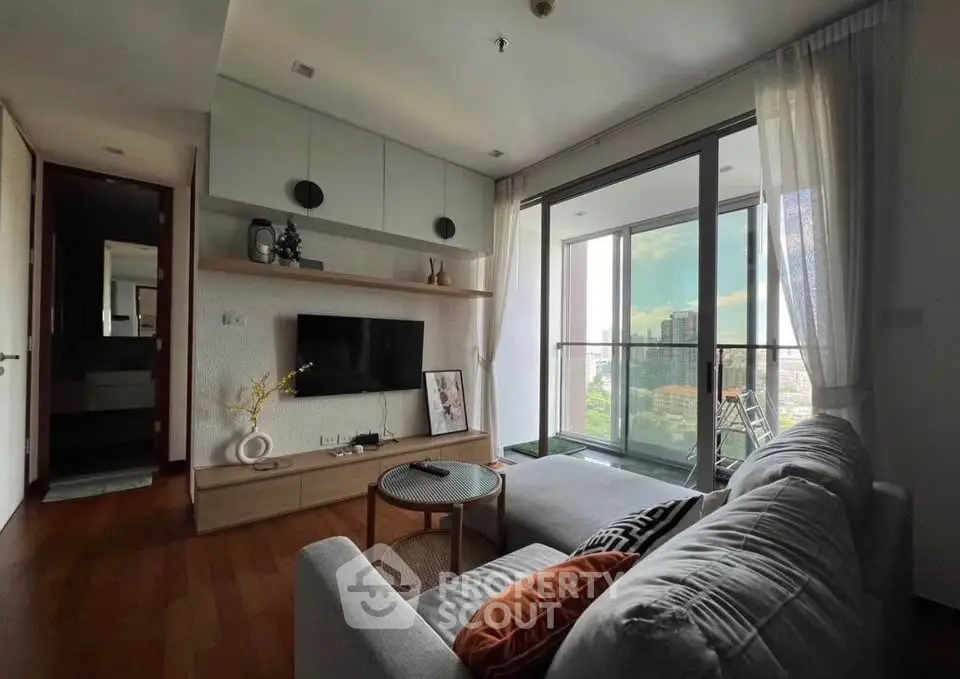 Modern living room with large balcony and city view, featuring stylish decor and cozy seating area.