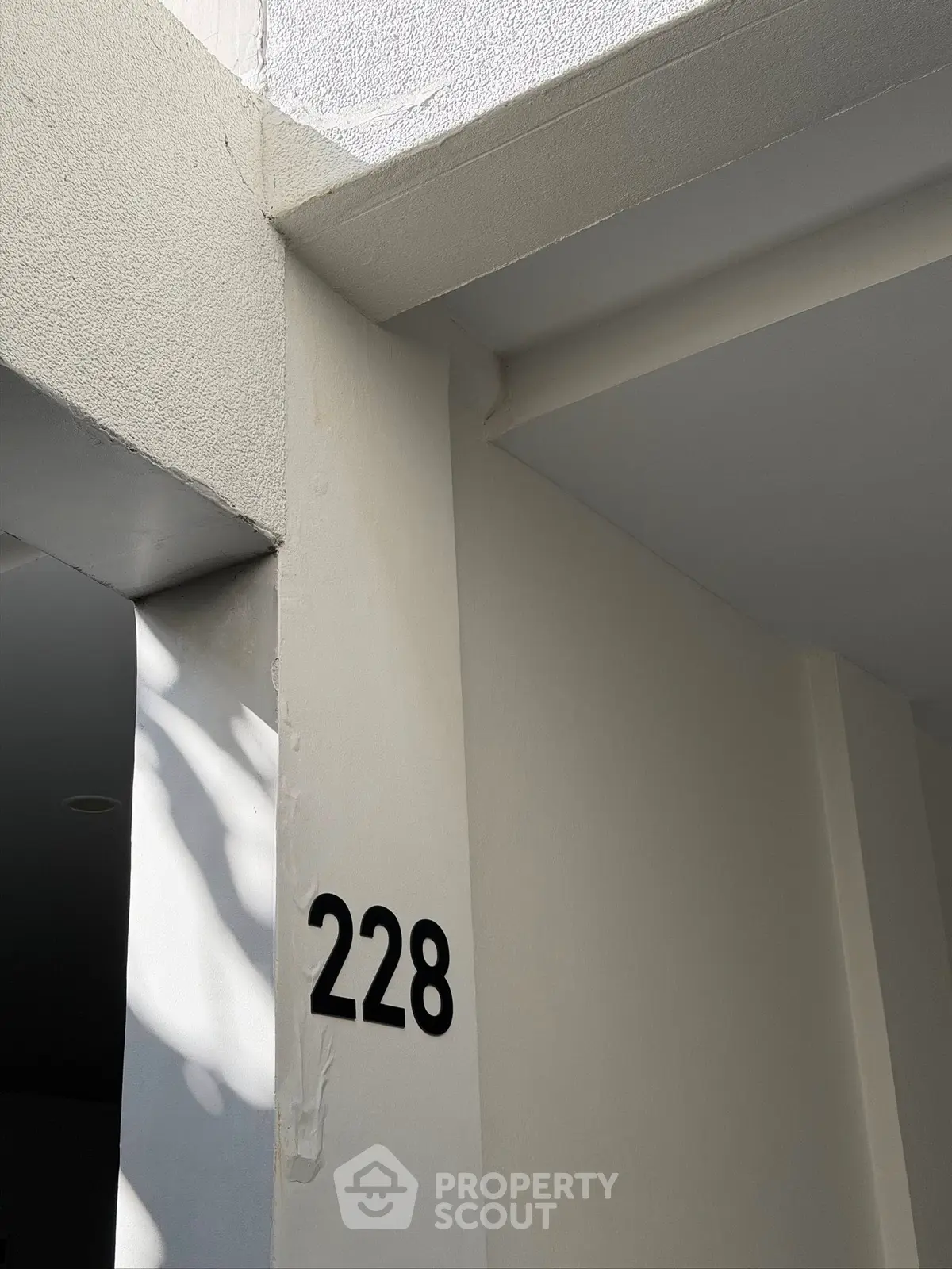 Modern building entrance with number 228, showcasing sleek architectural design.