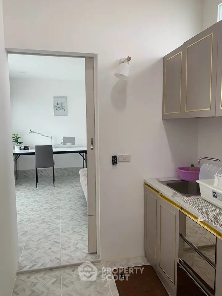 Modern compact kitchen with sleek cabinets and view into a minimalist study area.