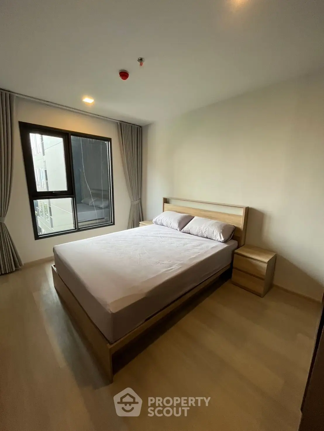 Modern bedroom with large window and minimalist wooden furniture in a cozy apartment.