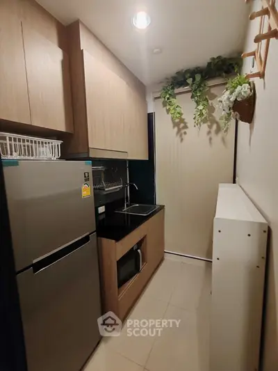 Modern compact kitchen with sleek cabinetry and stainless steel appliances in a cozy apartment.