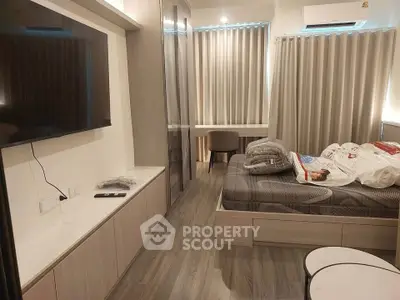 Modern bedroom with sleek design, featuring a wall-mounted TV, stylish furniture, and cozy ambiance.