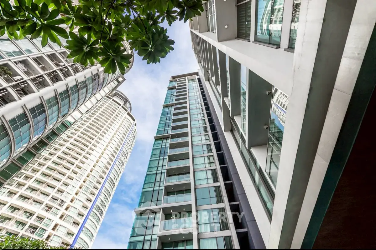 Stunning modern high-rise building with glass facade and lush greenery, perfect for urban living.