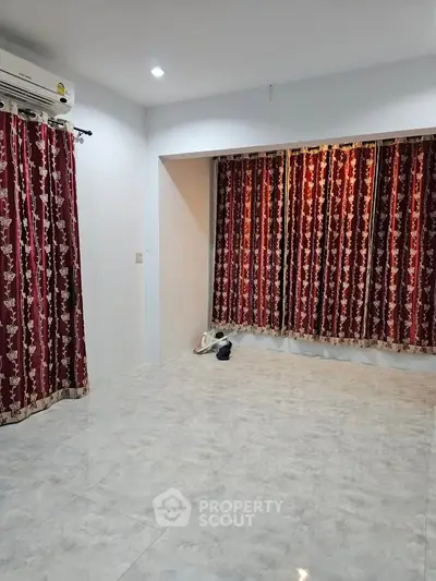 Spacious living room with elegant red curtains and marble flooring