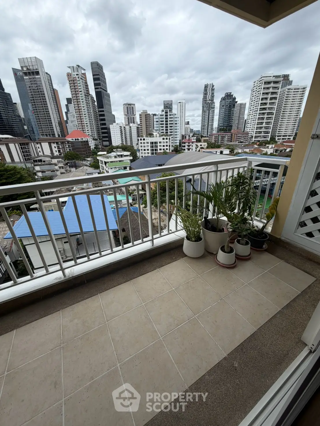 Spacious balcony with city skyline view and potted plants, perfect for urban living.