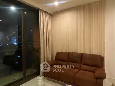 Cozy living room with leather sofa and city view through large glass doors