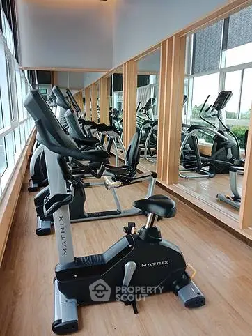 Modern gym with exercise equipment and mirrored walls in a bright, spacious setting.