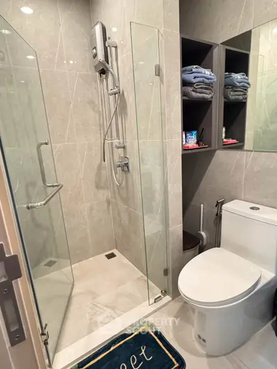 Modern bathroom with glass shower, sleek toilet, and towel storage, showcasing contemporary design and functionality.