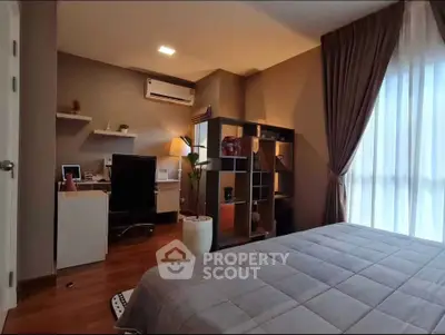 Modern bedroom with workspace, featuring stylish decor and natural light from large window.