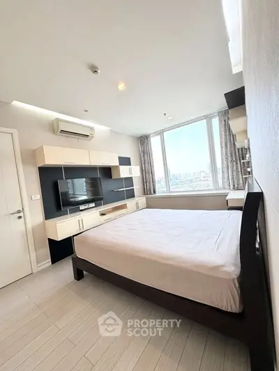 Spacious bedroom with city view, modern furniture, and ample natural light.