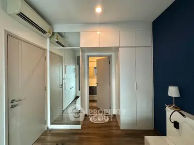 Modern bedroom with sleek white wardrobes and wooden flooring, featuring a stylish blue accent wall.
