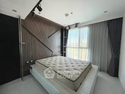 Modern bedroom with stylish wood paneling and large window for natural light.